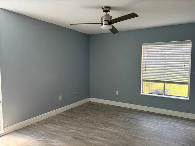 a view of an empty room with a window and wooden floor