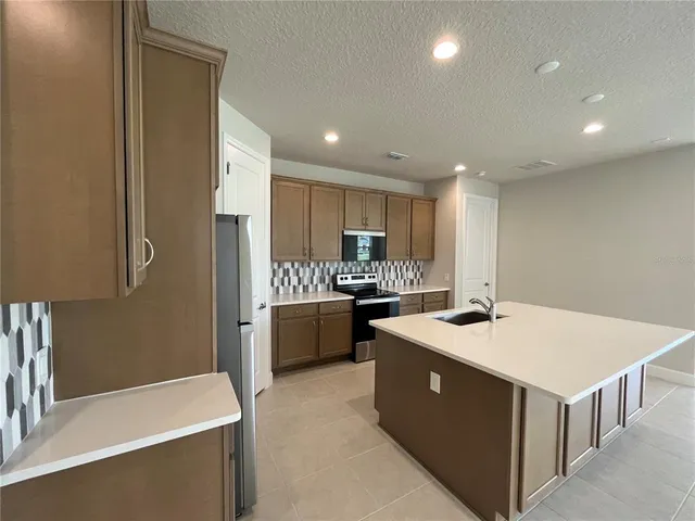 a large kitchen with kitchen island a sink a stove a refrigerator and a cabinets