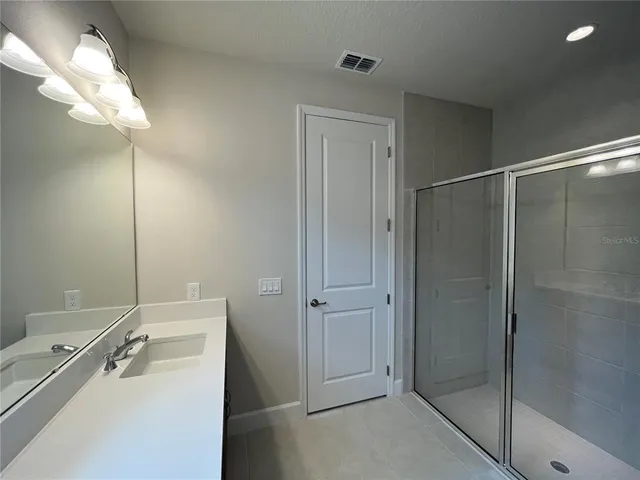 a bathroom with a shower a sink and mirror
