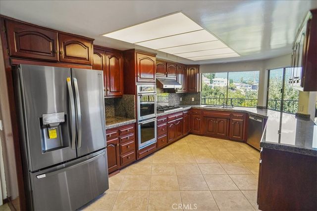 a kitchen with stainless steel appliances granite countertop a refrigerator a sink a stove and a refrigerator