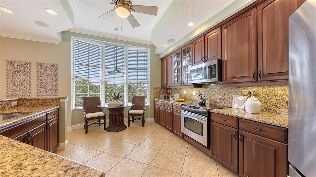 6465 Water Crest Way, Unit 404 Lakewood Ranch, FL 34202 - Photo 17 of 62 a kitchen with stainless steel appliances granite countertop a stove top oven a sink dishwasher a dining table and chairs with wooden floor