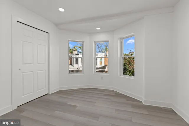 an empty room with wooden floor and window