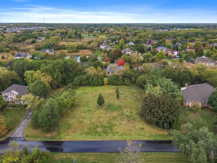 an aerial view of residential houses with outdoor space and trees