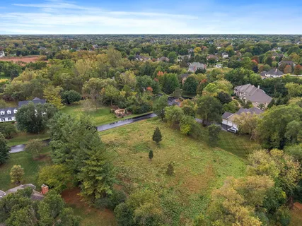 an aerial view of residential houses with outdoor space and trees