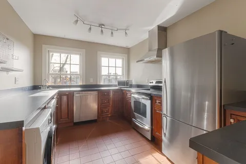 a kitchen with granite countertop a refrigerator sink stove and cabinets
