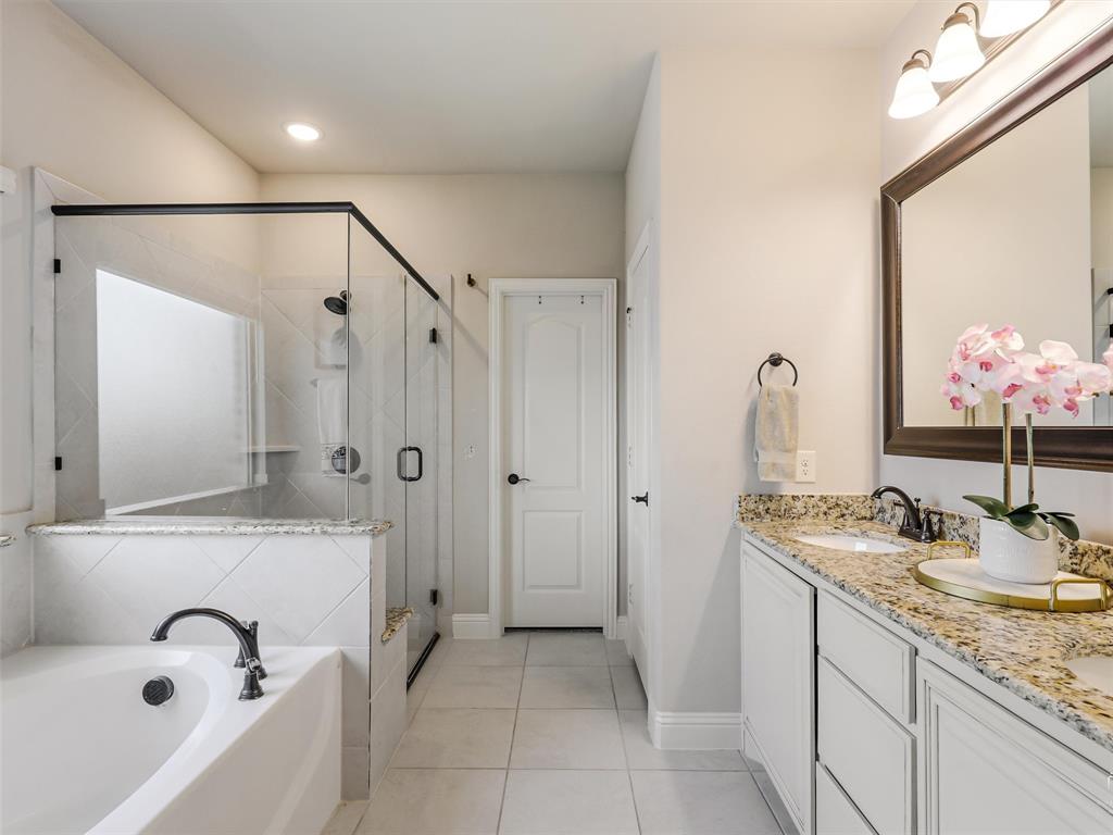 1216 Tree Shadow Lane Anna, TX 75409 - Photo 18 of 37 a bathroom with a granite countertop sink a mirror a shower and a bathtub
