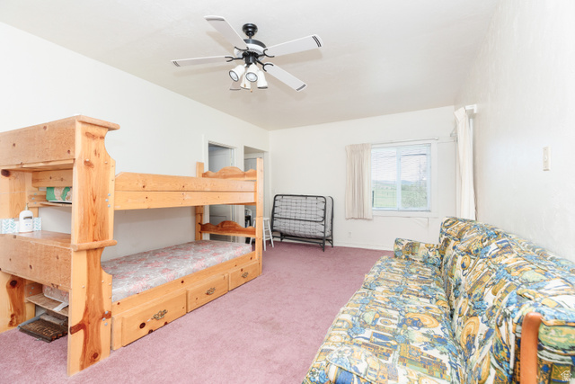 6746 North Capitol Hill Road Preston, ID 83263 - Photo 6 of 18 Spacious bedroom suite featuring built-in wooden bunk beds with integrated storage drawers, ceiling fan with lighting, plush carpeting throughout, and abundant natural light from large window with white curtain panels