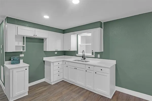 a room with a sink cabinets and a wooden floor