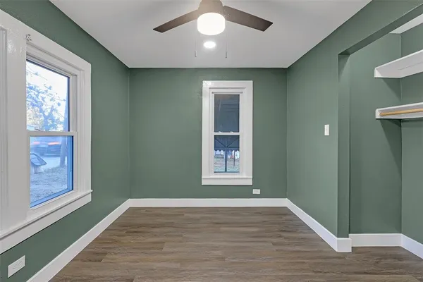 a view of an empty room with wooden floor and a window