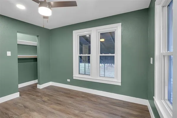 an empty room with wooden floor cabinet and windows