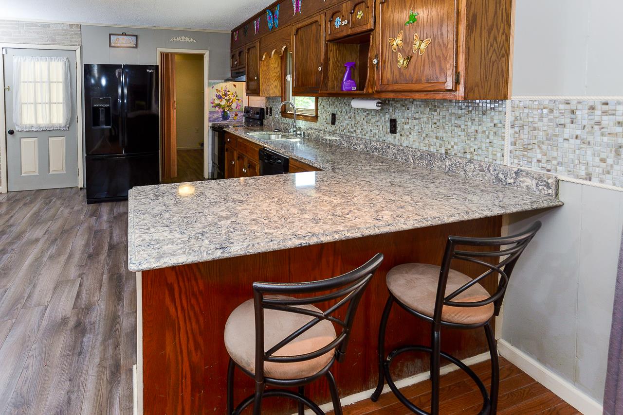 469 Limestone Road Elora, TN 37328 - Photo 16 of 30 a kitchen with stainless steel appliances granite countertop a table chairs in it and wooden floors