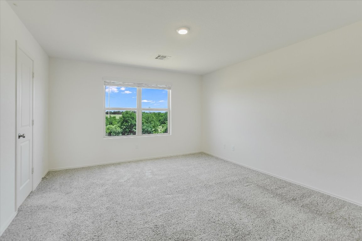 561 Greatest Gift Way Jarrell, TX 76537 - Photo 14 of 32 The primary suite is spacious with the bonus of a view to the green space behind the property.
