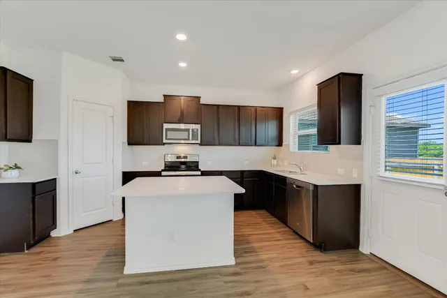 a large kitchen with stainless steel appliances a large counter top a stove a refrigerator and a sink