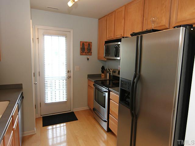 9712 Layla Avenue Raleigh, NC 27617 - Photo 12 of 25 a kitchen with a refrigerator a stove a sink and a window