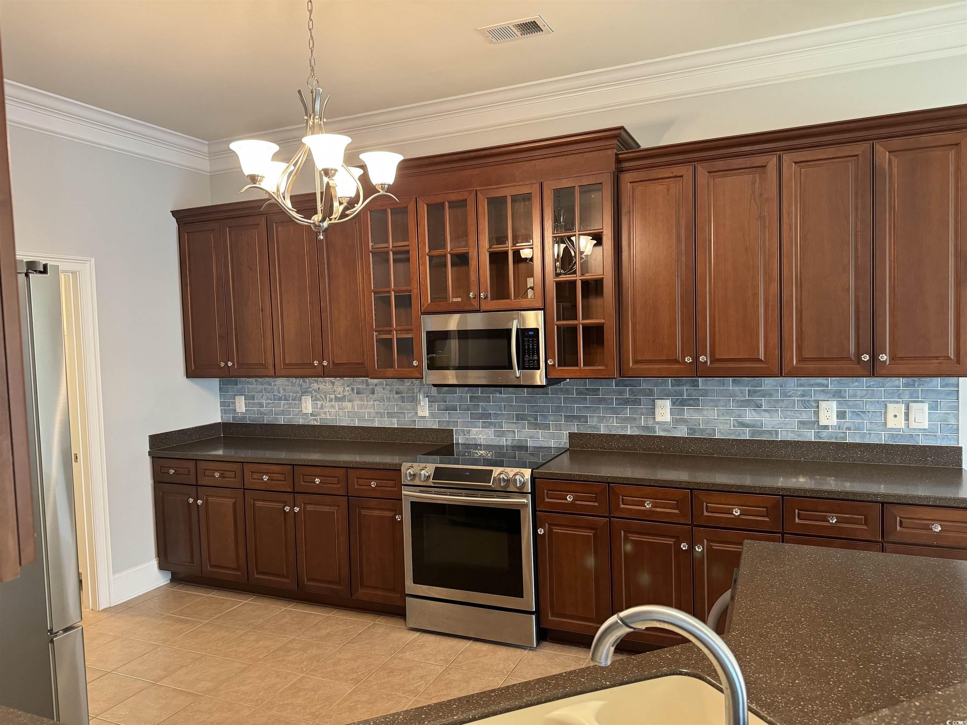 249 Venice Way, Unit 3105 Myrtle Beach, SC 29577 - Photo 12 of 40 Kitchen featuring appliances with stainless steel finishes, tasteful backsplash, ornamental molding, light tile patterned floors, and a notable chandelier