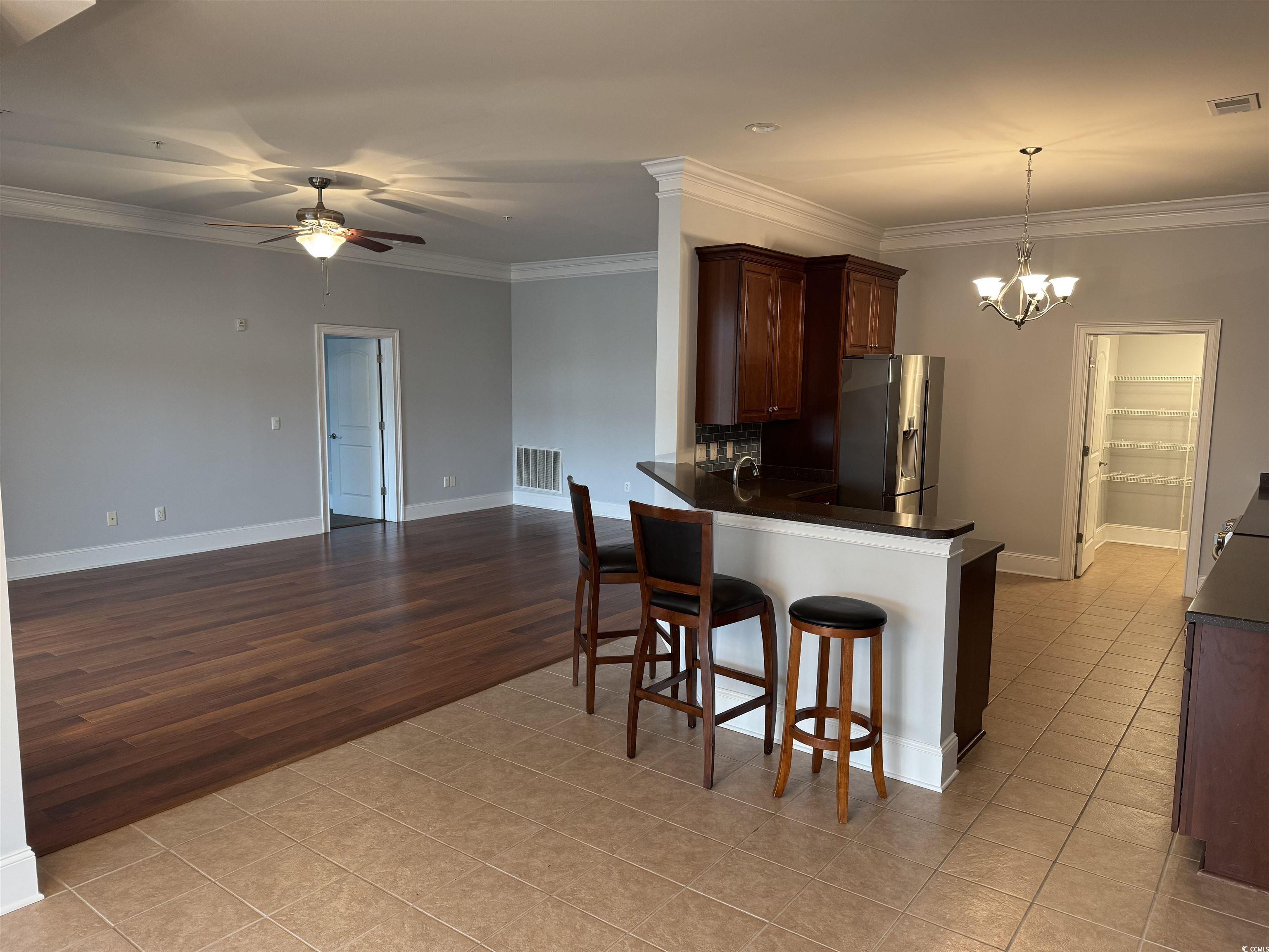 249 Venice Way, Unit 3105 Myrtle Beach, SC 29577 - Photo 5 of 40 Kitchen with kitchen peninsula, stainless steel fridge, a breakfast bar area, light tile patterned flooring, and ornamental molding