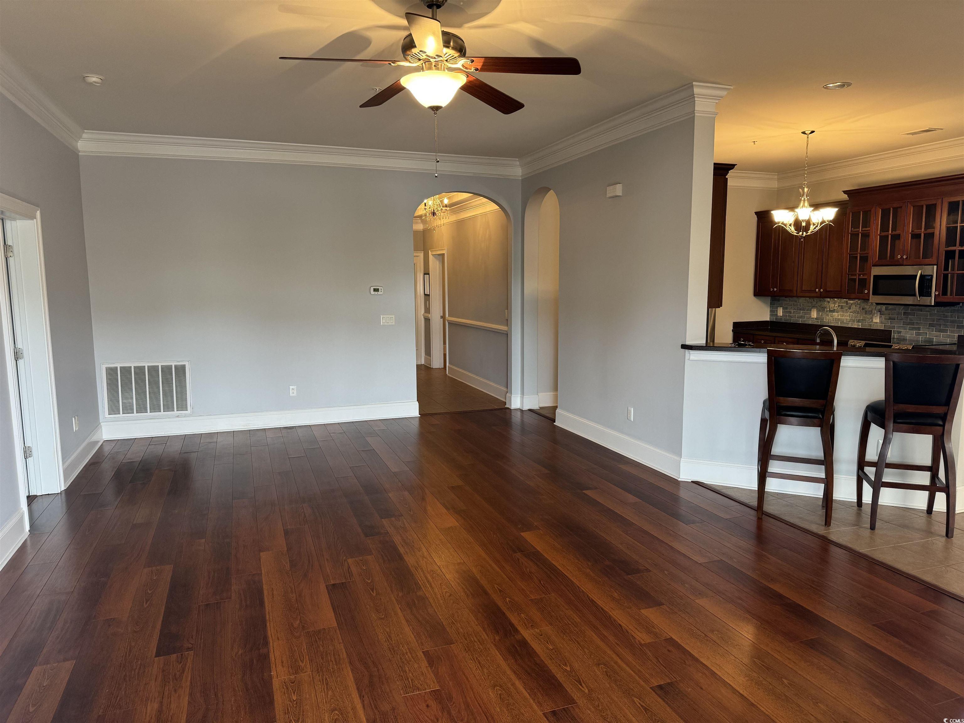 249 Venice Way, Unit 3105 Myrtle Beach, SC 29577 - Photo 7 of 40 Unfurnished living room featuring ceiling fan with notable chandelier, dark wood-type flooring, ornamental molding, and sink