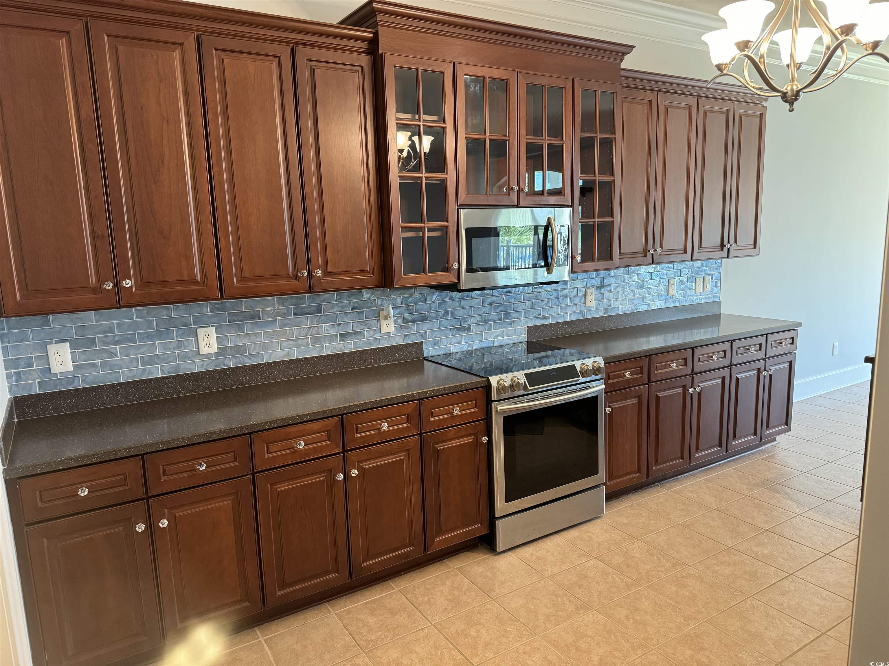 249 Venice Way, Unit 3105 Myrtle Beach, SC 29577 - Photo 9 of 40 Kitchen with hanging light fixtures, a notable chandelier, crown molding, light tile patterned floors, and appliances with stainless steel finishes