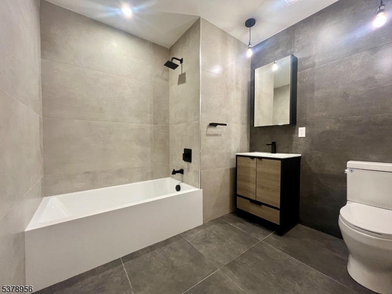 59 McWhorter Street, Unit 405 Newark, NJ 07105 - Photo 3 of 9 a bathroom with a bathtub a mirror a sink and a toilet