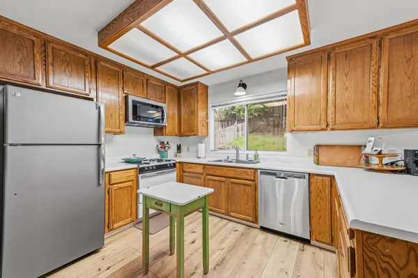 a kitchen with stainless steel appliances granite countertop a refrigerator a stove top oven a sink dishwasher and white cabinets with wooden floor