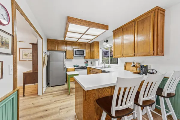 a kitchen with stainless steel appliances granite countertop a refrigerator a stove a sink dishwasher and white cabinets with wooden floor