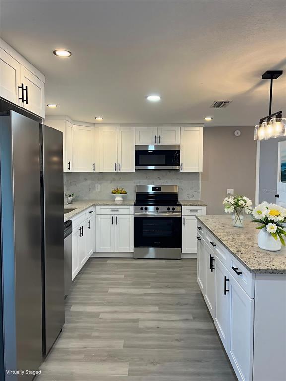 3800 Darlington Road Holiday, FL 34691 - Photo 6 of 36 a large kitchen with stainless steel appliances granite countertop a stove a sink dishwasher a refrigerator and a oven with wooden floor