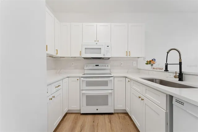 a kitchen with granite countertop a sink and white cabinets