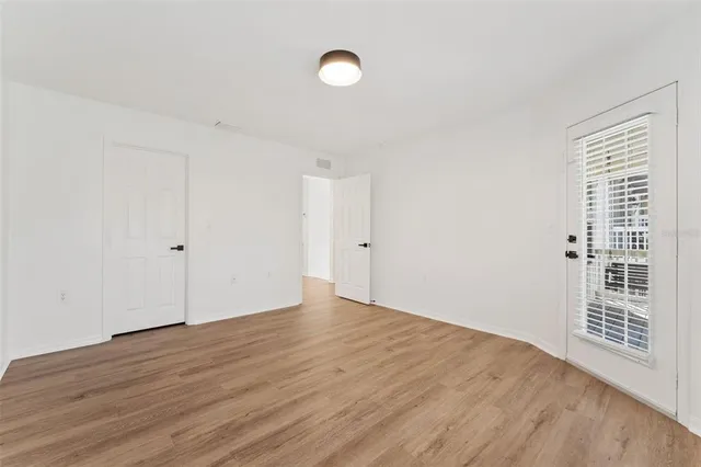 an empty room with wooden floor and windows