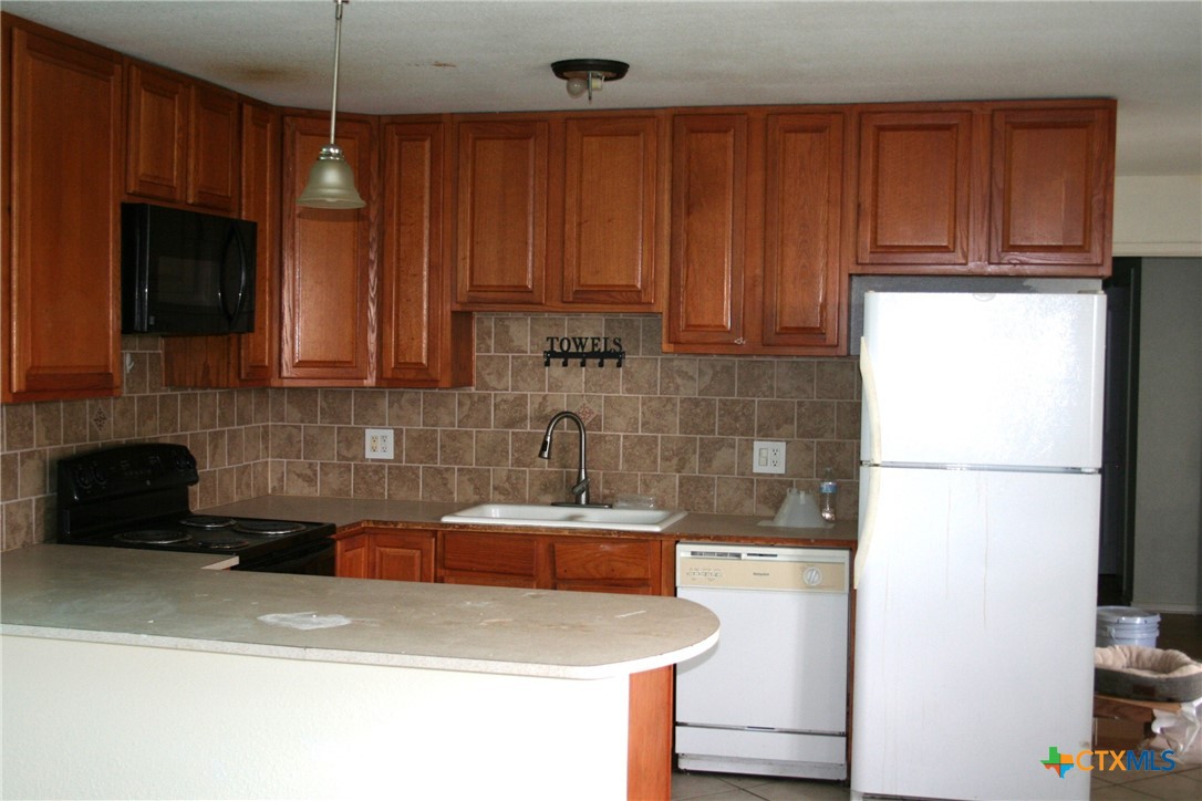 3402 Little Nolan Road Killeen, TX 76542 - Photo 24 of 37 a kitchen with a refrigerator a stove a microwave and cabinets