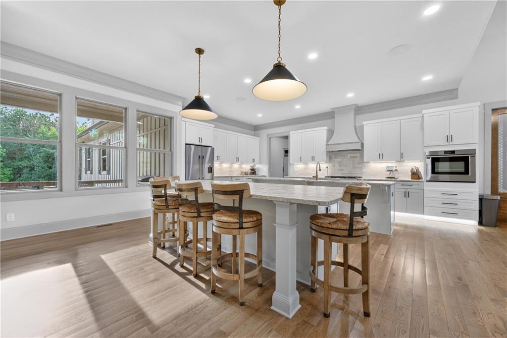 4726 Crestview Way Flowery Branch, GA 30542 - Photo 12 of 48 a kitchen with stainless steel appliances kitchen island granite countertop a stove a refrigerator a sink a dining table and chairs with wooden floor