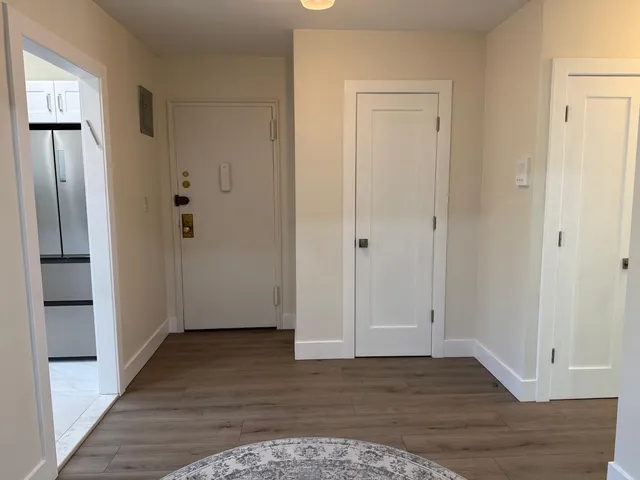 a view of an empty room with wooden floor and a bathroom