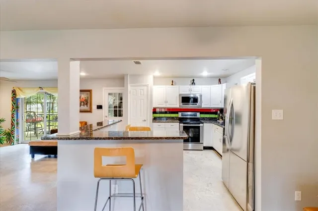 a kitchen with kitchen island granite countertop a refrigerator and a stove top oven