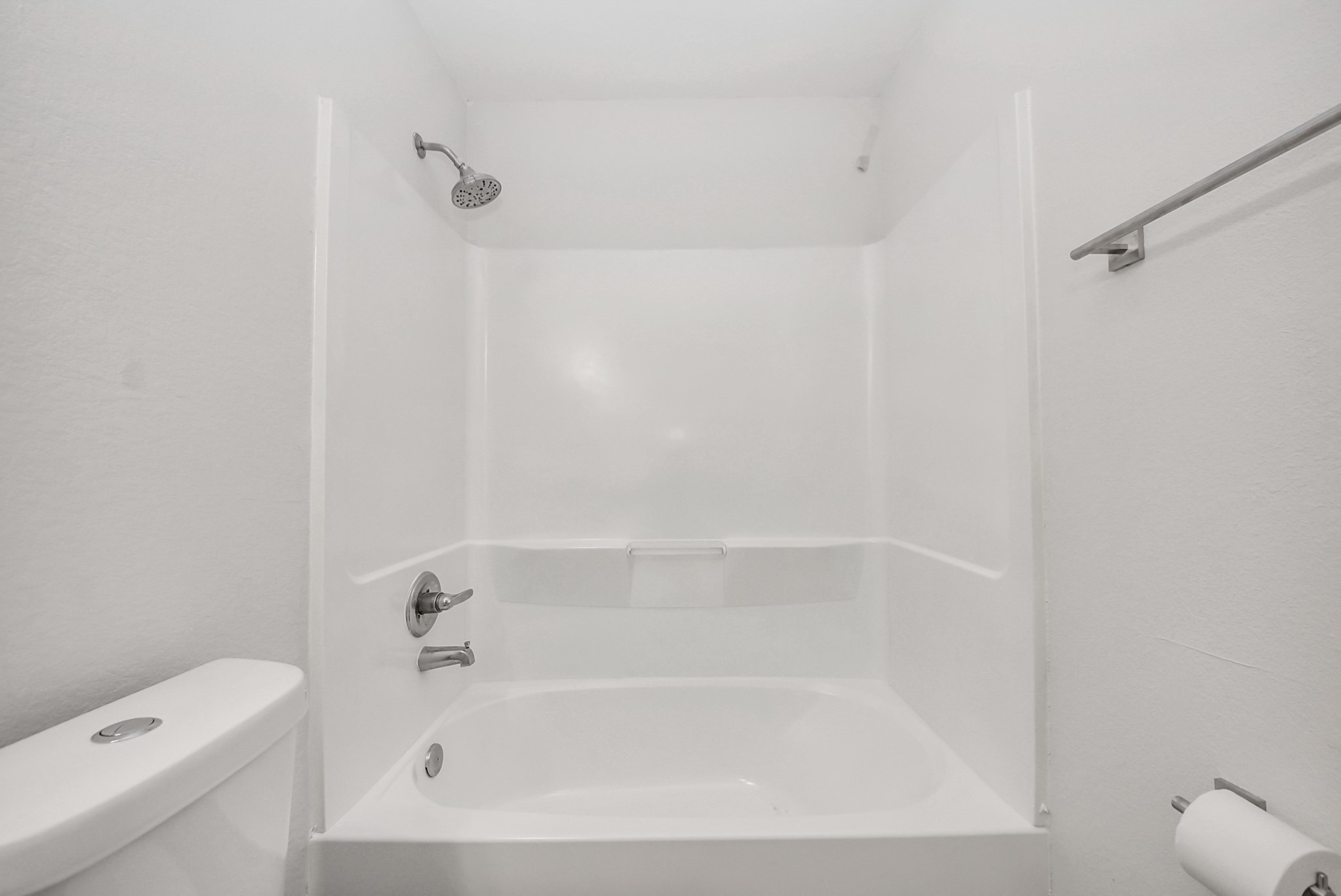 16124 Brettwood Lane Splendora, TX 77372 - Photo 18 of 40 This bathroom features a clean, modern design with a white bathtub and shower combo, complete with a sleek showerhead. It includes a toilet and a towel bar, offering practicality and comfort.