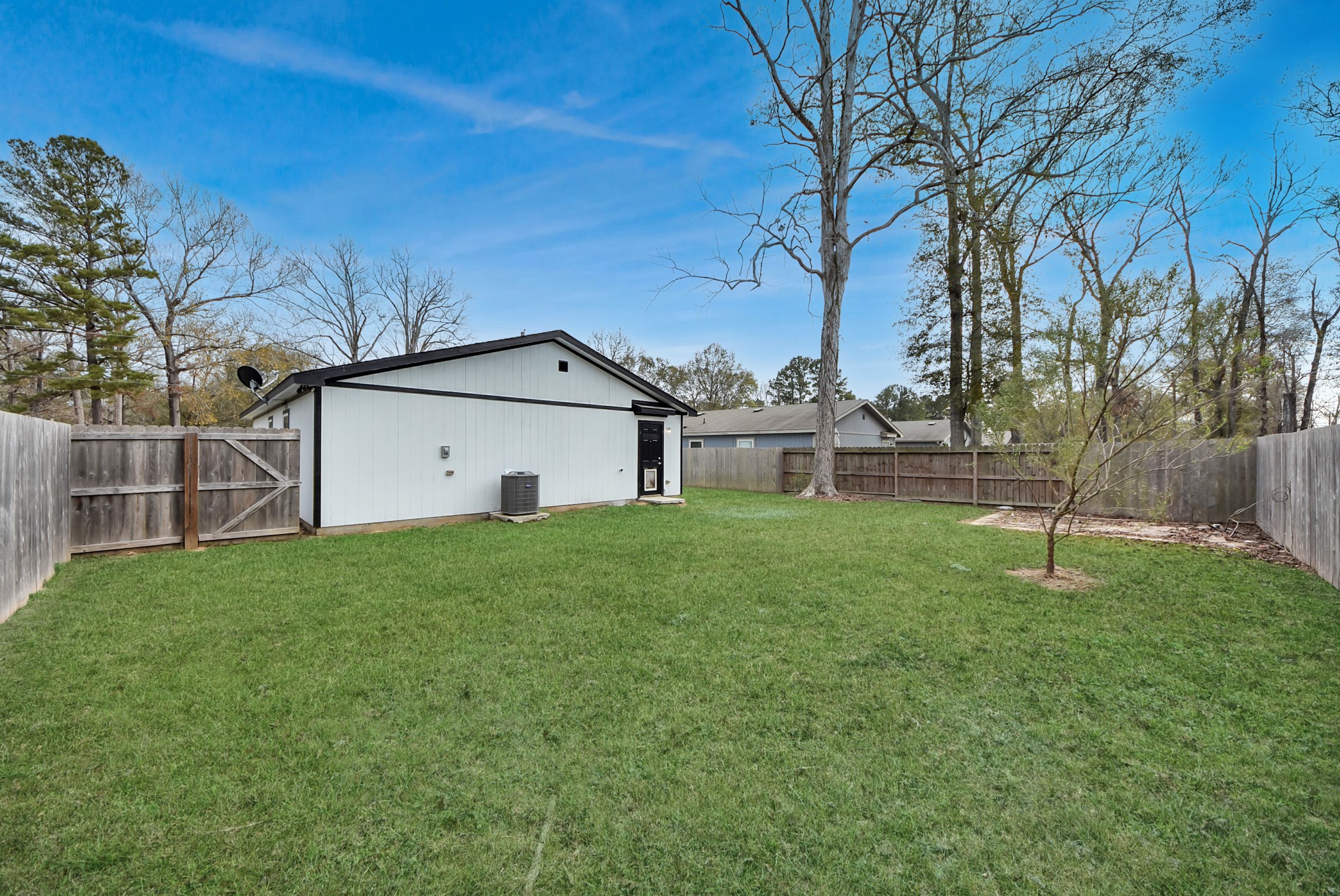 16124 Brettwood Lane Splendora, TX 77372 - Photo 34 of 40 Spacious, fenced backyard with a small outbuilding, mature trees, and well-maintained lawn—ideal for outdoor activities.