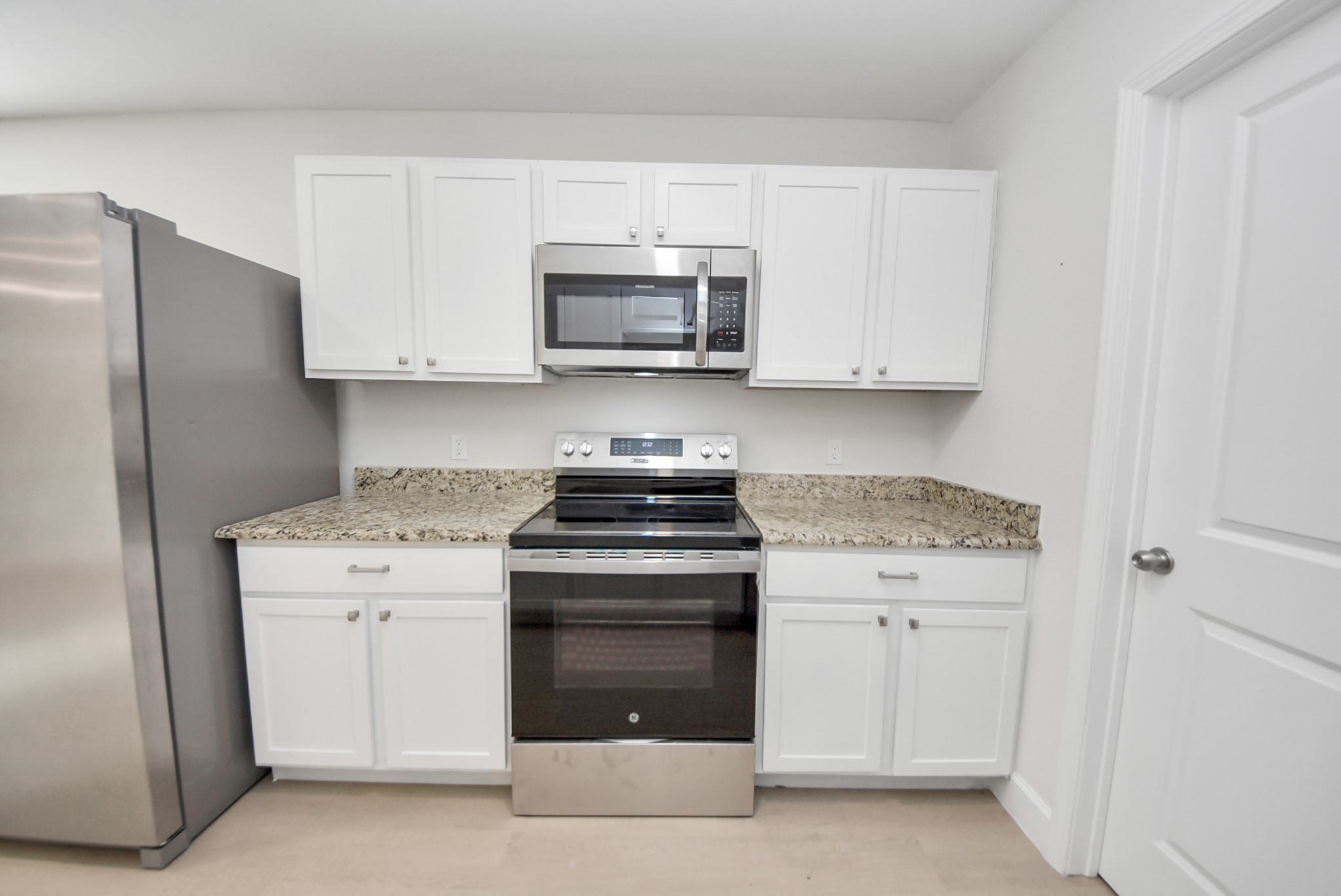 16124 Brettwood Lane Splendora, TX 77372 - Photo 9 of 40 Modern kitchen with stainless steel appliances, granite countertops, and white cabinetry, offering a clean and functional cooking space.