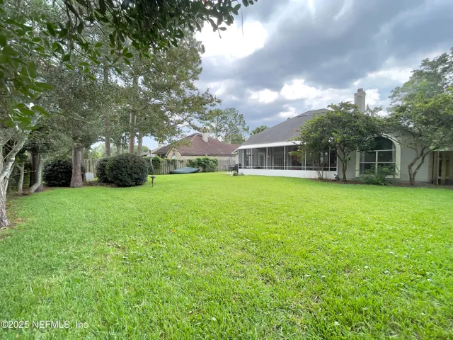 a view of a house with a big yard and large trees