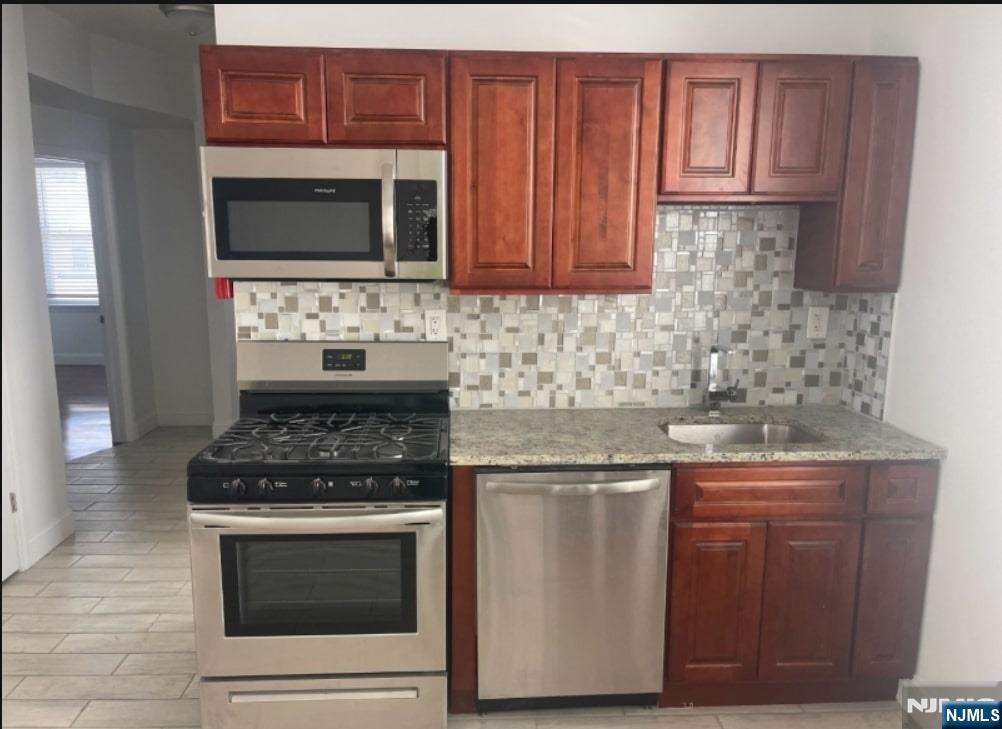 421-423 Leslie Street, Unit 1L Newark, NJ 07112 - Photo 3 of 14 a kitchen with stainless steel appliances granite countertop a stove microwave and cabinets