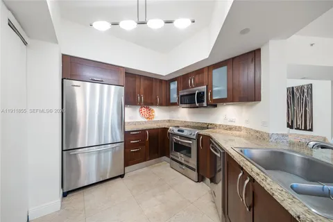 a kitchen with stainless steel appliances granite countertop a refrigerator a sink dishwasher a stove top oven a refrigerator with wooden cabinets
