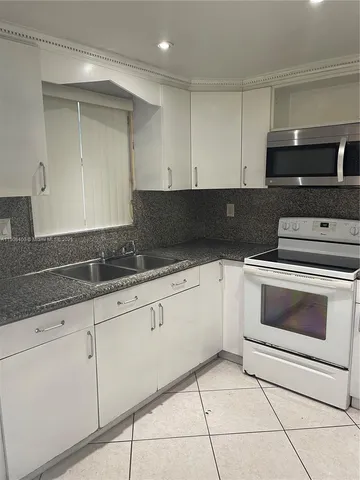 a kitchen with granite countertop white cabinets and appliances