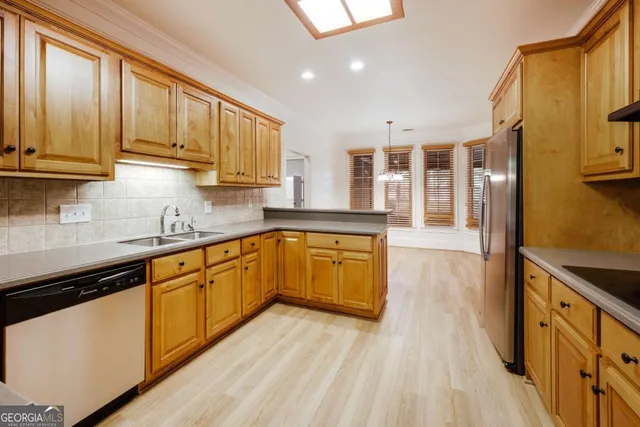 a kitchen with stainless steel appliances granite countertop a stove a sink and a refrigerator with wooden floors