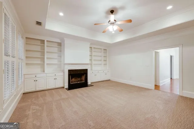 an empty room with windows and fireplace