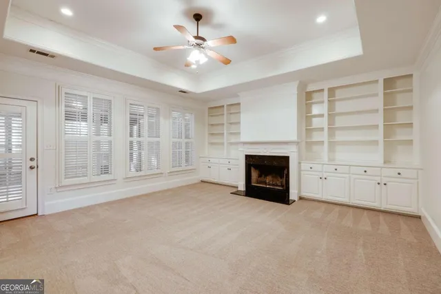 an empty room with chandelier fan and windows