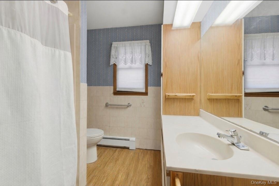 191 Rose Road Woodbourne, NY 12788 - Photo 20 of 47 Bathroom featuring curtained shower, vanity, wallpapered walls, a wainscoted wall, and a baseboard radiator