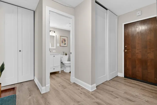 a view of a hallway with wooden floor and a bathroom