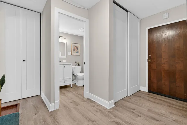 a view of a hallway with wooden floor and a bathroom