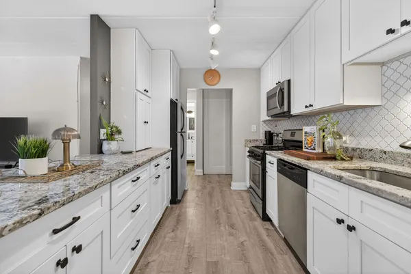 a large kitchen with stainless steel appliances granite countertop a lot of counter space and wooden floor