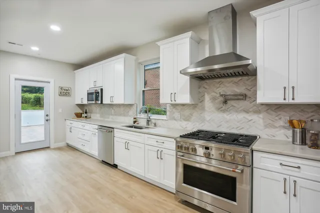 a kitchen with stainless steel appliances white cabinets and a stove a sink