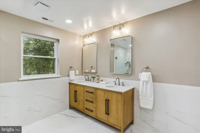 a bathroom with a double vanity sink window and mirror