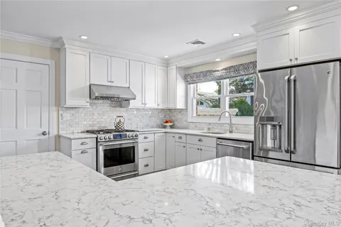 a kitchen with kitchen island granite countertop wooden floors and white cabinets