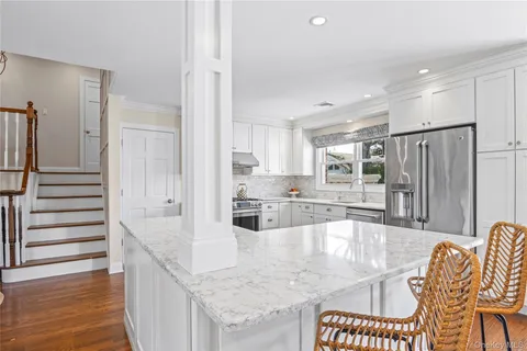 a kitchen with stainless steel appliances kitchen island granite countertop a stove top oven a sink a dining table and chairs with wooden floor